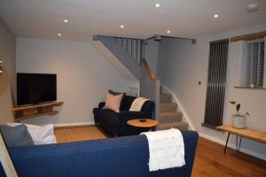 a living room with a blue couch and a staircase at Dairy in the Black Mountains in Abergavenny