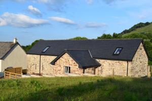 duży kamienny dom z czarnym dachem w obiekcie Dairy in the Black Mountains w mieście Abergavenny