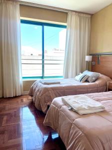 ein Hotelzimmer mit 2 Betten und einem großen Fenster in der Unterkunft Impecable, amplio y moderno departamento en la mejor ubicacion de la Ciudad de Mendoza in Mendoza