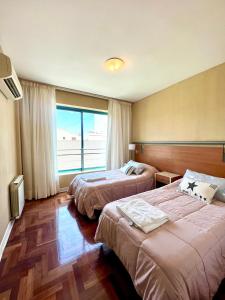 ein Hotelzimmer mit 2 Betten und einem großen Fenster in der Unterkunft Impecable, amplio y moderno departamento en la mejor ubicacion de la Ciudad de Mendoza in Mendoza