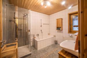 a bathroom with a shower and a tub and a sink at Ferienhaus Sonne Harz und Sterne in Hohegeiß +15 photos