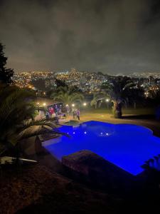 a large blue swimming pool with a city at night at Casa Zeta in Viña del Mar