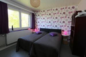 a bedroom with a bed with purple pillows and a window at Gîte du Baroudeur in Spa