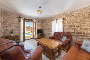 een woonkamer met lederen meubels en een bakstenen muur bij Villa Zinnia in Fabci