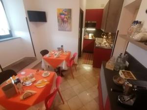 a room with two tables and a kitchen with red cabinets at Hotel Centrale in Cascia