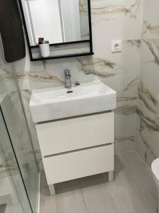 uma casa de banho com um lavatório branco e um espelho. em ALCAZABA PREMIUM CON VISTAS em Sierra Nevada