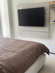 1 dormitorio con TV de pantalla plana en la pared en Apto Terraços do Atlântico, en Fortaleza