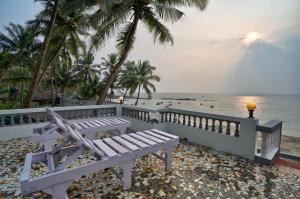Villa Seafront Goa في أنجونا: مقعد أبيض على الشاطئ بالقرب من المحيط