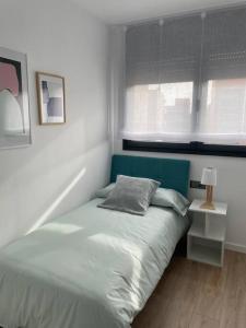 1 dormitorio con 1 cama con cabecero azul y ventana en Estrénalo a minutos de BCN, en Sant Feliu de Llobregat