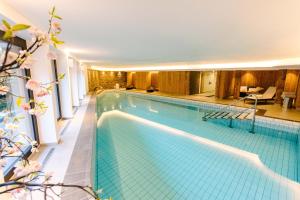 a large swimming pool in a building at Seven Alpina Boutique Hotel in Klosters Serneus