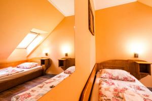 Duas camas num quarto com paredes cor de laranja em Pensiune si Restaurant Anda em Gheorgheni