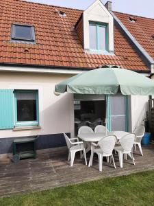 eine Terrasse mit einem Tisch, Stühlen und einem Sonnenschirm in der Unterkunft Gîte Cap Goéland - Maison chaleureuse au cœur du site des 2 Caps in Audinghen