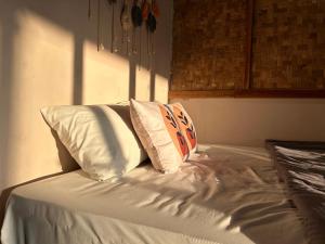 a white bed with two pillows on top of it at Paddies Homestay New in Cipaku-gede