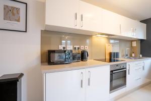 a kitchen with white cabinets and a microwave at Newly Refurbished Great location Free Parking in Leeds