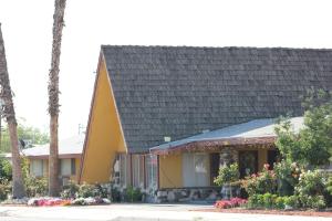 une maison avec un toit gris et des fleurs dans l'établissement Cinderella Motel, à Wasco
