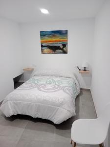 1 dormitorio con 1 cama, 1 silla y 1 pintura en Apartamentos los carros 2 en Guadix