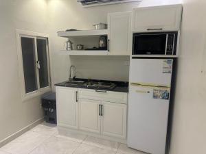 uma cozinha com armários brancos, um micro-ondas e um frigorífico em غيمة للشقق الفندقية em Jeddah