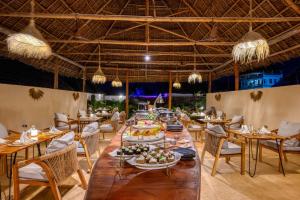 a long dining room with tables and chairs and chandeliers at Safaya Luxury Villas - Adults only in Nungwi
