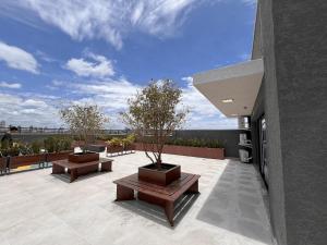 a patio with benches and trees on a building at Easy Life Campus PUC by Xtay in Curitiba