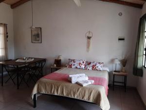 1 dormitorio con 1 cama con 2 almohadas y mesa en PIQUILLIN CASA PARA DOS en Las Rabonas