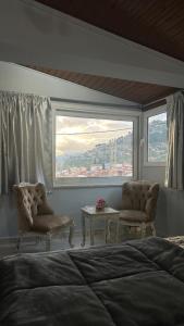 1 dormitorio con 1 cama, 2 sillas y ventana en Με θέα το Κάστρο, en Nafpaktos