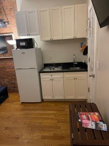 Midtown Nest 1 bedroom Self Serviced Apartment في نيويورك: مطبخ فيه دواليب بيضاء وثلاجة بيضاء