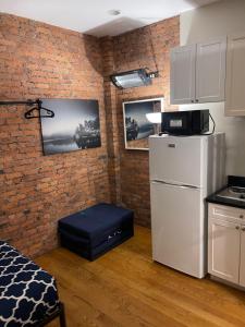 a kitchen with a white refrigerator and a brick wall at Midtown Nest 1 bedroom Self Serviced Apartment in New York