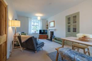 a living room with a table and a blue chair at Meadow View - Cosy townhouse with patio garden & parking in Kendal
