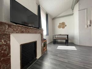 a living room with a fireplace with a flat screen tv at L'appartement Marceau - 55m2 - Carcassonne centre in Carcassonne
