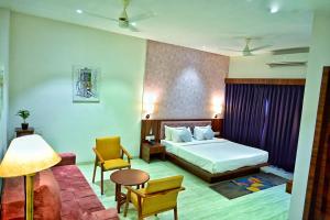 a hotel room with a bed and a table and chairs at The One Hotel Nashik in Nashik