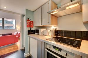 a kitchen with a stove top oven next to a living room at Crown Apartments 104 by Week2Week in Newcastle upon Tyne