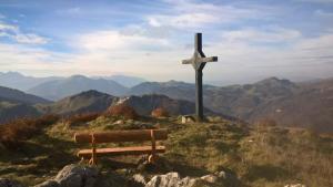 a wooden cross on top of a hill with a bench at Les Silenes in Bellevaux
