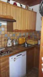 a kitchen with wooden cabinets and a sink and a stove at Les Silenes in Bellevaux