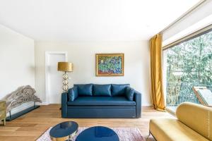 a blue couch in a living room with a window at Boulogne Billancourt - Schuman 1bdr in Boulogne-Billancourt