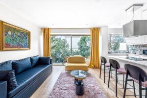 a living room with a blue couch and a kitchen at Boulogne Billancourt - Schuman 1bdr in Boulogne-Billancourt