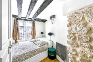 - une chambre avec un lit et un mur en pierre dans l'établissement Grands Boulevards - Vivienne 1bdr, à Paris