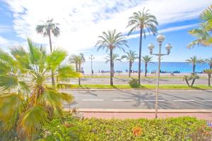 Promenade des Anglais - Sea View 2bdr في نيس: شارع فيه نخيل والمحيط في الخلف