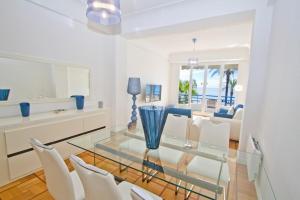 une salle à manger avec une table en verre et des chaises blanches dans l'établissement Promenade des Anglais - Sea View 2bdr, à Nice