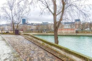 une rivière avec un arbre et des bâtiments en arrière-plan dans l'établissement Ile Saint Louis - Quai d'Orleans 2bdr, à Paris