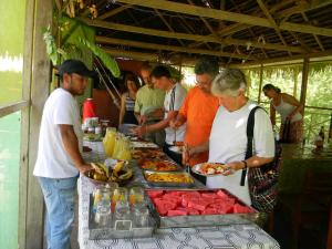 a group of people standing around a buffet of food at Jacamar Lodge Expeditions in Iquitos