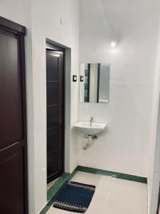 a bathroom with a sink and a mirror and a door at Puthookadans Mareena Lodge in Kottayam