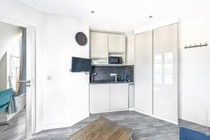 a white kitchen with white cabinets and a table at Studio Mac Mahon - Champs Elysees in Paris