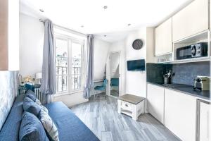 Il comprend un salon avec un canapé bleu et une cuisine. dans l'établissement Champs Elysees - Mac Mahon Studio, à Paris