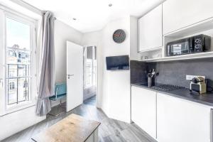 a kitchen with white cabinets and a large window at Studio Mac Mahon - Champs Elysees in Paris