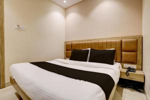 ムンバイにあるHotel Al Ibrahimのベッドルーム1室(大型ベッド1台、木製ヘッドボード付)