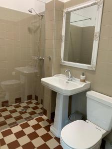 een badkamer met een wastafel, een toilet en een spiegel bij Kaunas Embassy Apartments in Kaunas