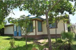 una casa con ventanas azules y un árbol en The D'Lux Home, Homa Bay, en Marinde