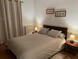 een slaapkamer met een groot wit bed met 2 lampen bij Cal mosso in Collsuspina
