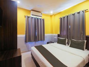 a bedroom with a bed with yellow walls and curtains at Map Inn in Morjim