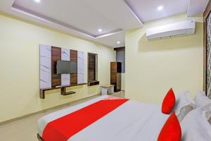 1 dormitorio con 1 cama con almohadas rojas y TV en OYO Hotel Golden, en Vadodara